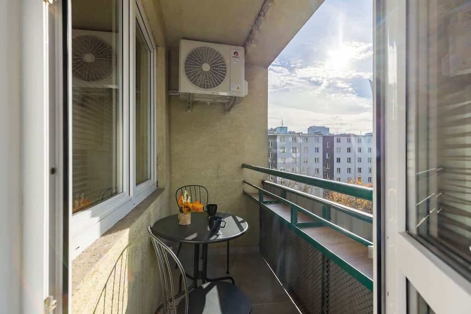 A cozy balcony with a small seating area, overlooking the surrounding cityscape.
