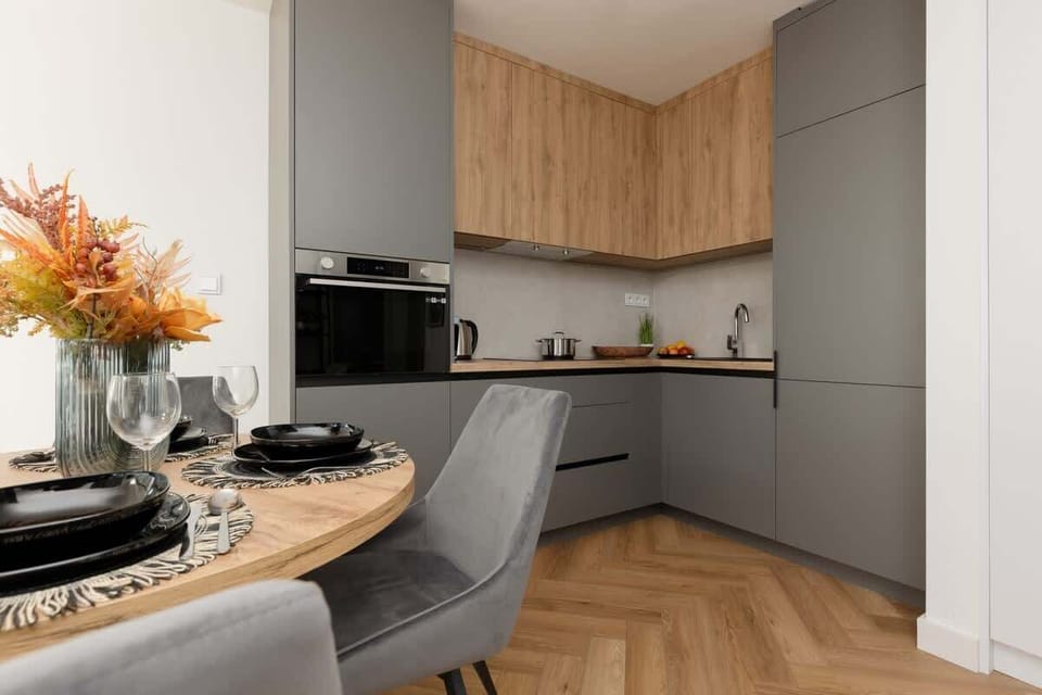 A modern kitchen with a dark gray and wooden finish, complemented by an elegant black countertop.
