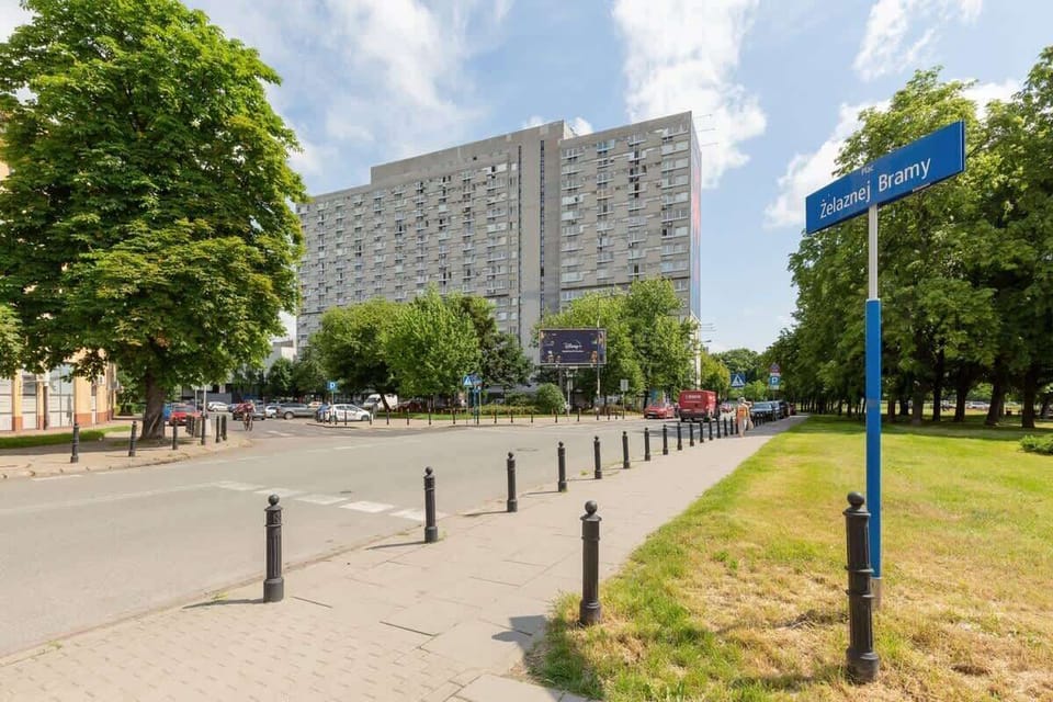 A pedestrian and cycling path next to a residential complex, with street signs and lush green trees.
