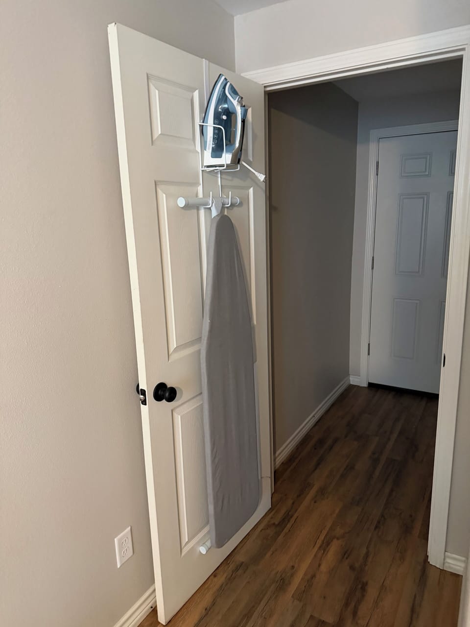 Laundry room with iron and ironing board.
