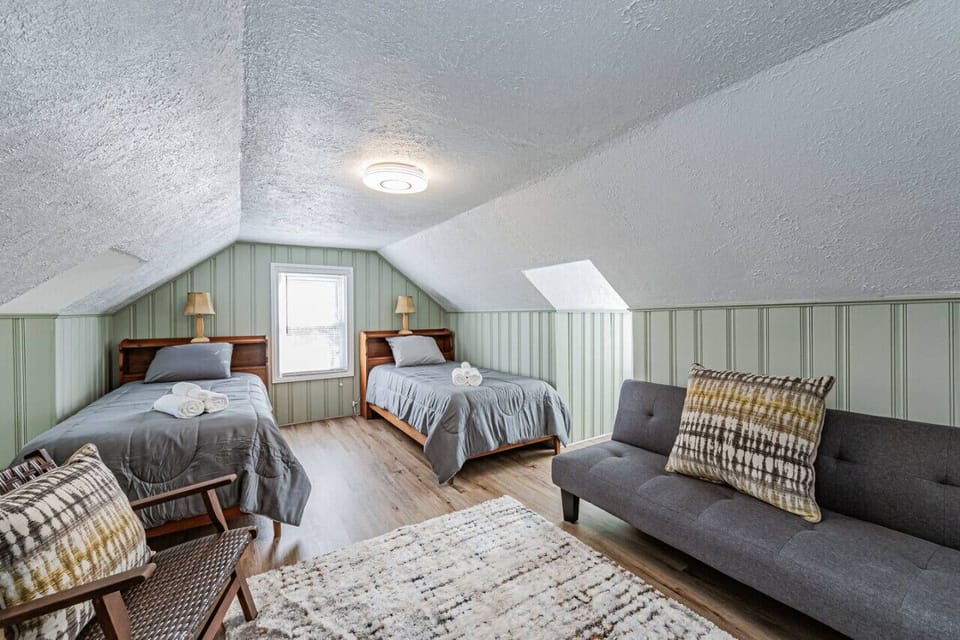 Nestled on the second floor, this charming bedroom boasts two twin beds, a seating area, and a cape cod ceiling for a unique and cozy vibe. Watch your favorite shows on the flat-screen Roku TV before drifting off to sleep!