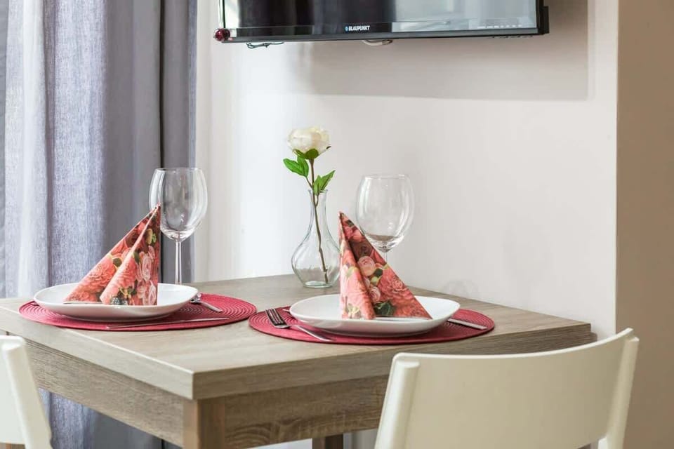A dining area set for two, with a window view and elegant table settings.

