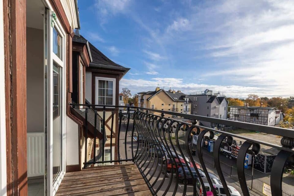 A charming balcony with a black railing, overlooking a scenic European street.

