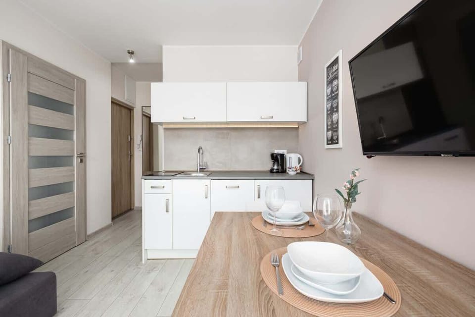 An open-plan kitchen and dining space with a mounted TV and stylish decor.

