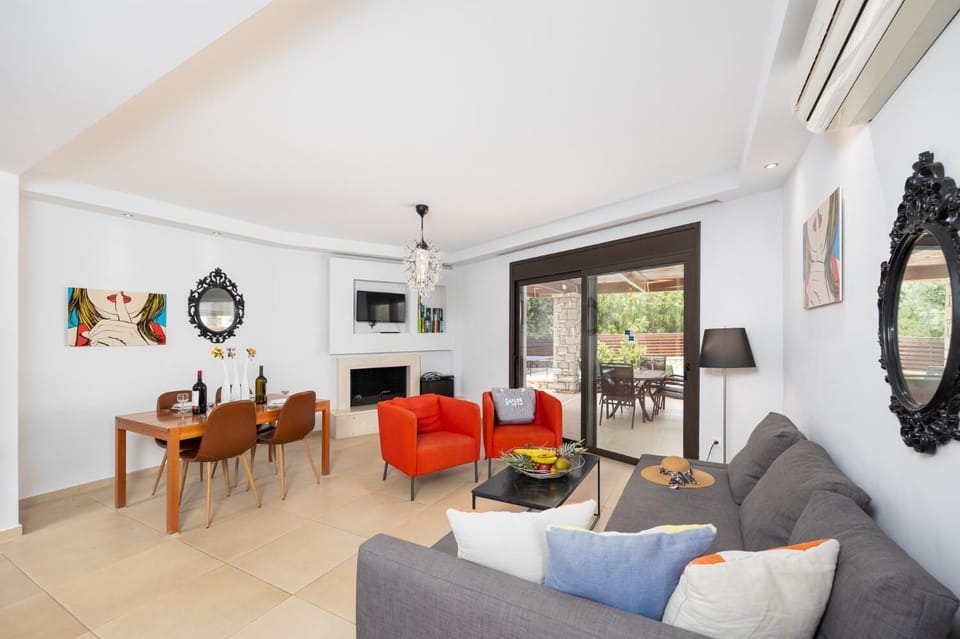 Open-plan living room with sofa, dining area, kitchen, ornamental fireplace, A/C, WiFi internet, and satellite TV