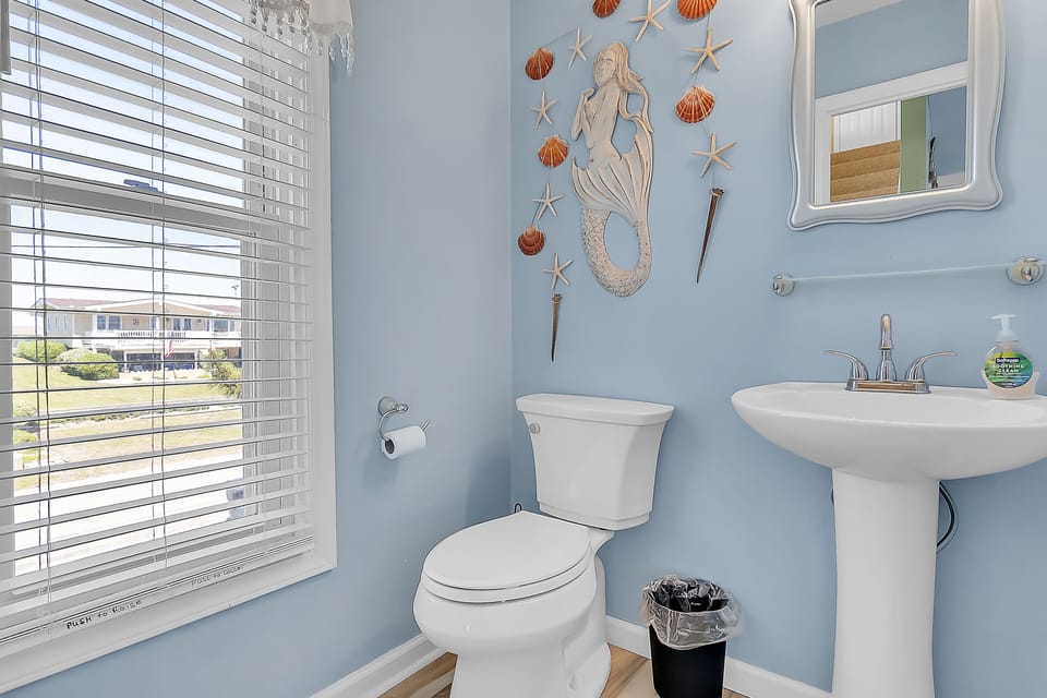 You'll love freshening up in this charming coastal-themed bathroom with whimsical mermaid decor and ocean-inspired touches.