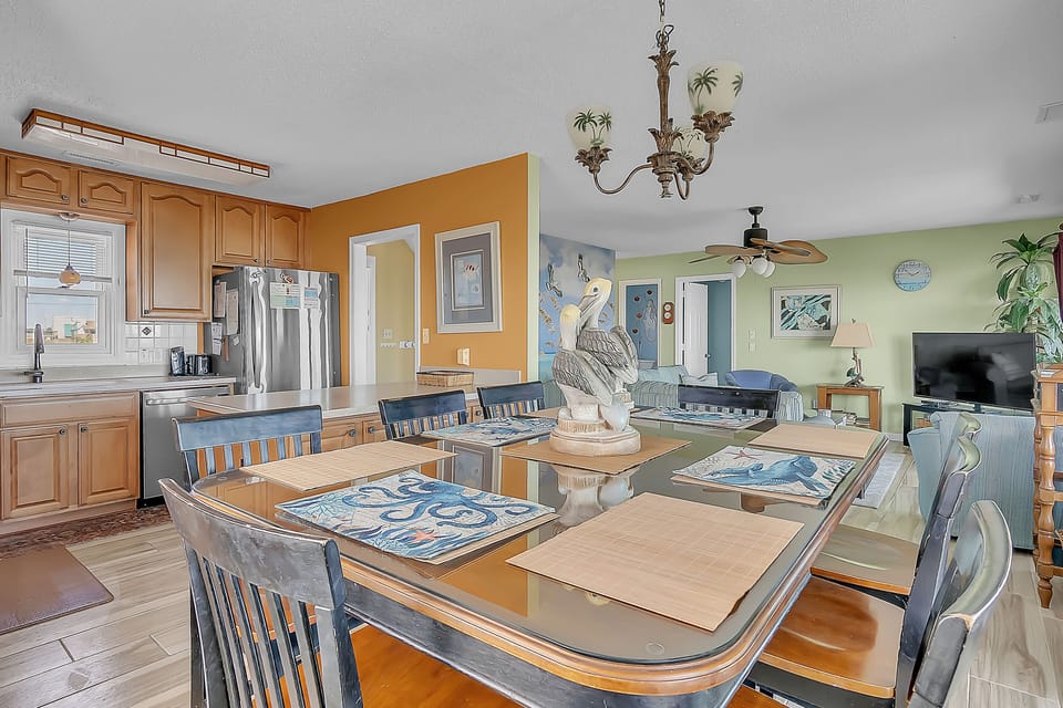 Your open dining and kitchen space features coastal charm with ocean-themed touches, perfect for memorable meals together.