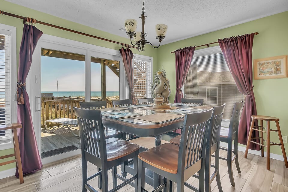 Savor meals with stunning ocean views through your private balcony doors in this charming coastal dining space.