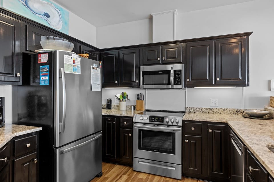 Your gourmet kitchen features stainless steel appliances, granite counters, and rich dark cabinetry - perfect for preparing memorable meals.