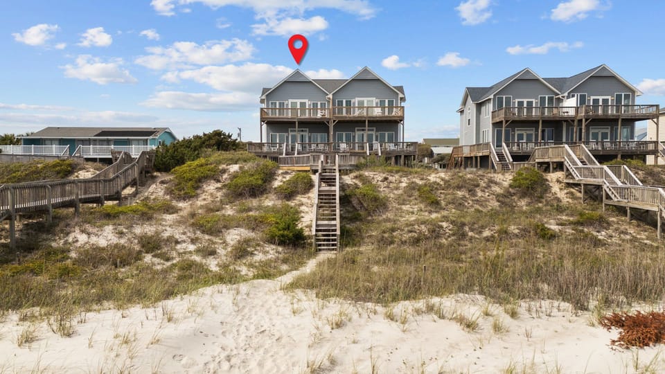 Beachfront rental homes with direct sand access via wooden walkways, surrounded by natural dune vegetation.