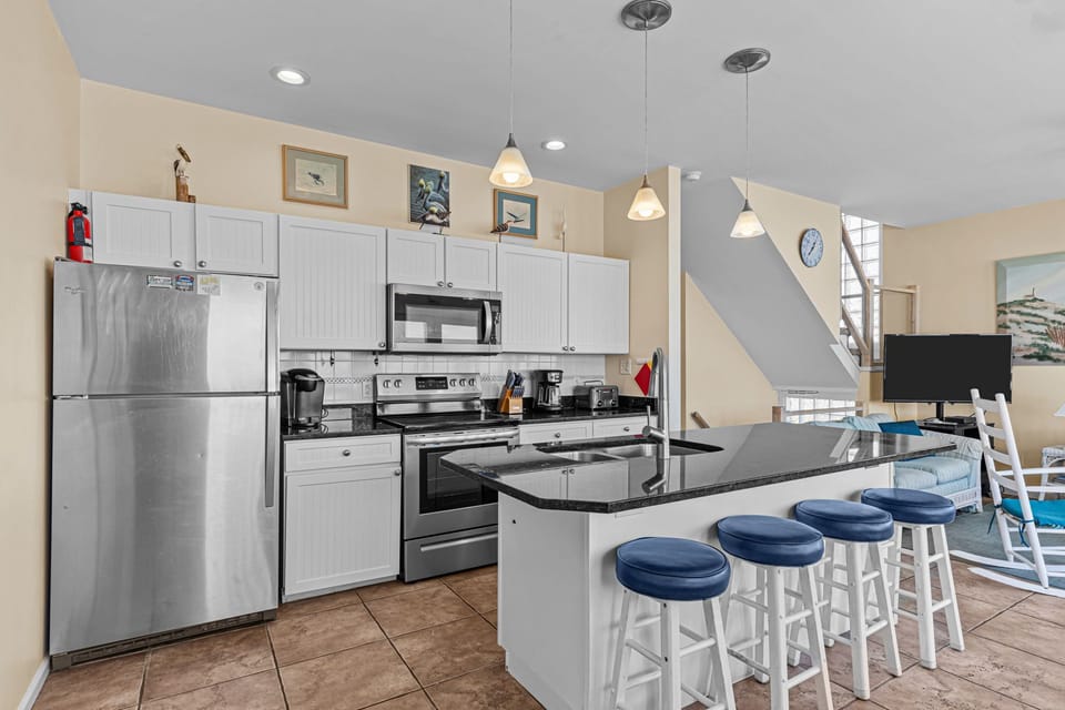 Your fully equipped kitchen features stainless steel appliances, granite countertops, and cozy bar seating for casual meals together.