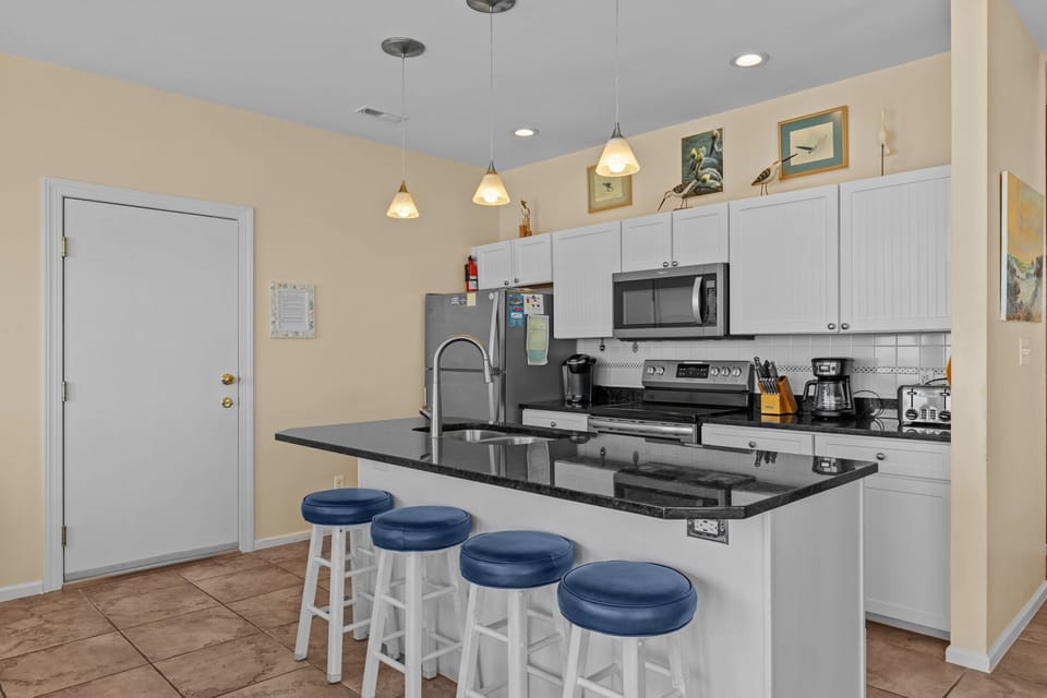Your fully equipped kitchen awaits with granite counters, stainless appliances, and bar seating perfect for morning coffee or casual meals.