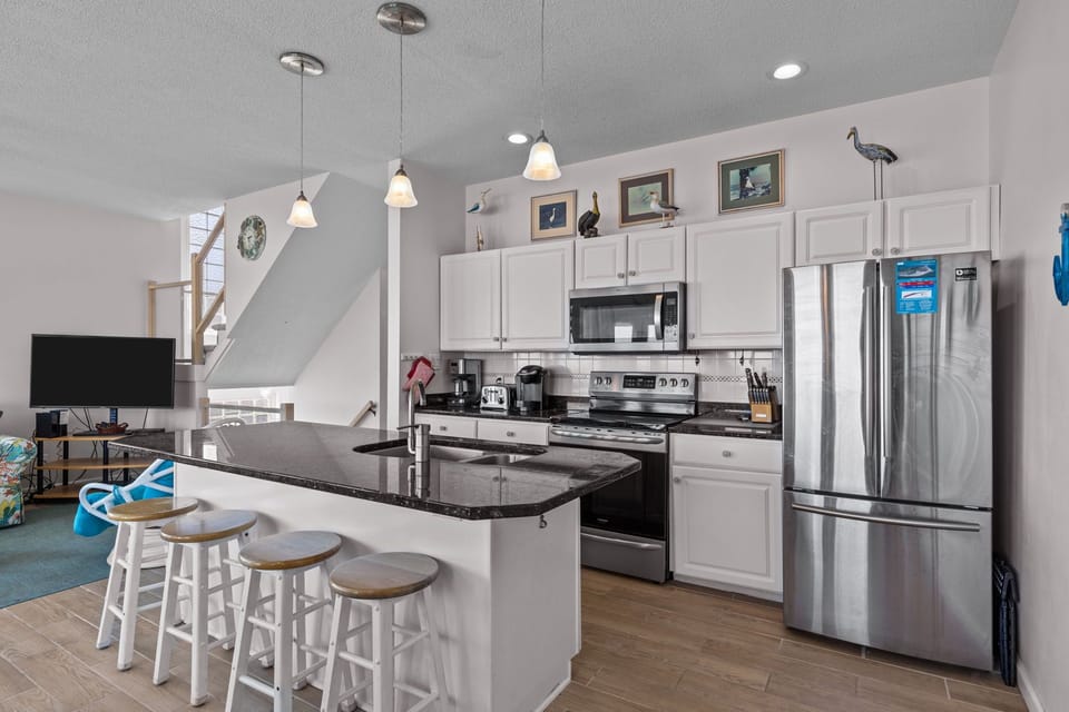 Your fully equipped kitchen features modern appliances, granite countertops, and a breakfast bar perfect for morning coffee or casual meals.