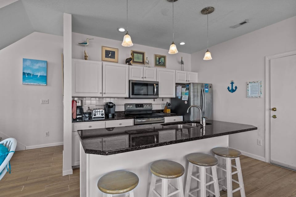 Your fully equipped kitchen features granite countertops, modern appliances, and a breakfast bar where you can enjoy morning coffee.