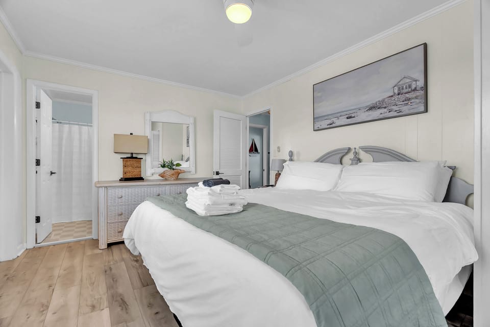 Sink into crisp white linens and coastal calm in your serene bedroom. Soft sage accents and beachside artwork set a peaceful tone, while plush towels and thoughtful touches ensure your comfort throughout your stay.