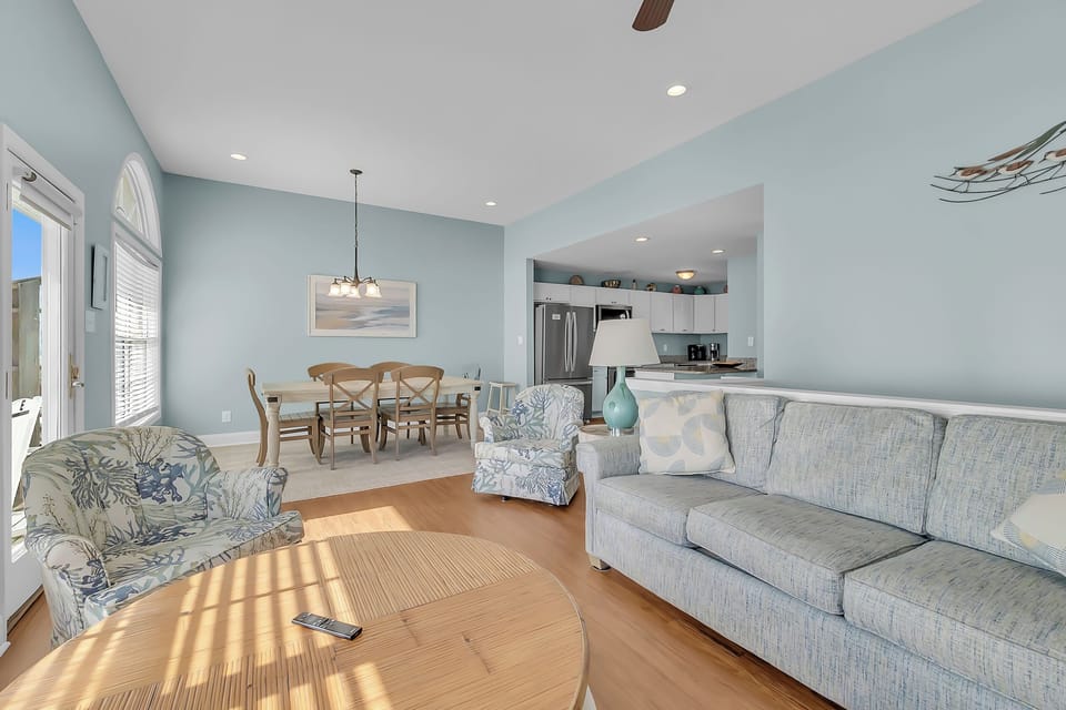 Relax in your bright, coastal-inspired living space with comfortable seating and an open kitchen—perfect for unwinding after beach days.