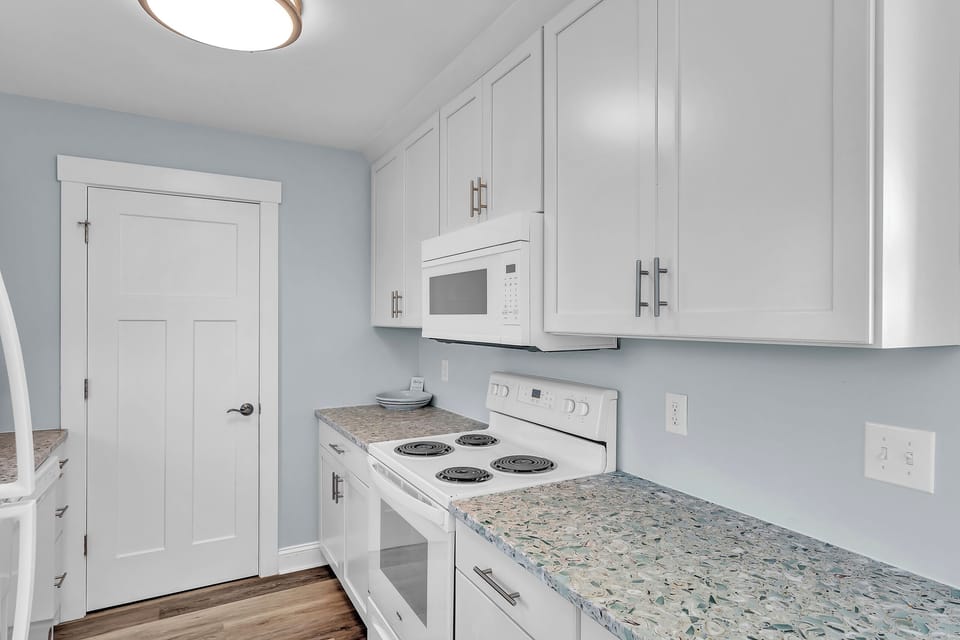 Your bright kitchen features crisp white cabinets, granite countertops, and all essential appliances for preparing delicious meals during your stay.