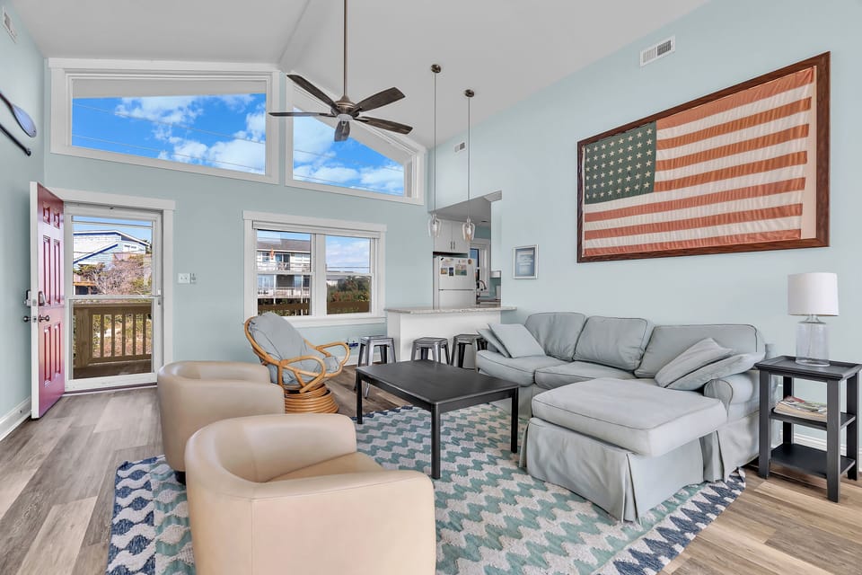 Relax in your bright living space with soaring ceilings, cozy sectional seating, and coastal views through expansive windows.