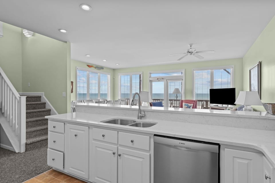Your kitchen island becomes the heart of beachside mornings, with white counters and ocean views creating perfect moments.