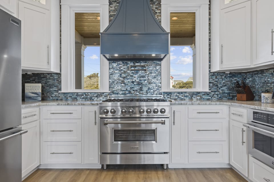 Cook gourmet meals in this stunning kitchen featuring professional-grade appliances, beautiful backsplash, and windows overlooking scenic views.