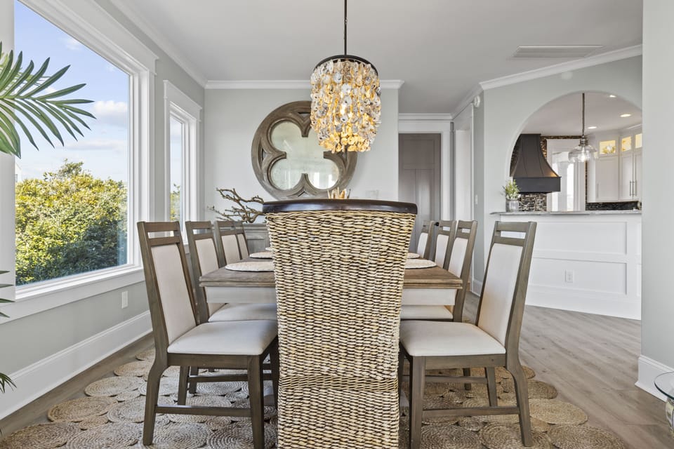 Gather around this elegant dining table where memorable meals await, bathed in natural light from stunning garden views.