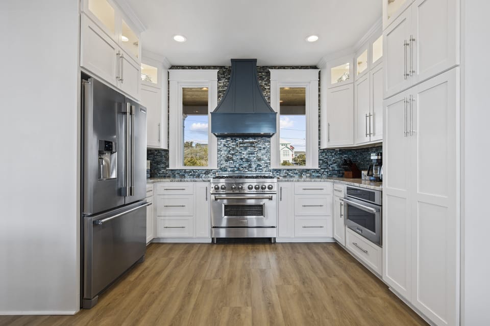 Your gourmet kitchen features premium stainless steel appliances, elegant white cabinetry, and stunning blue mosaic backsplash—perfect for creating memorable meals during your stay.