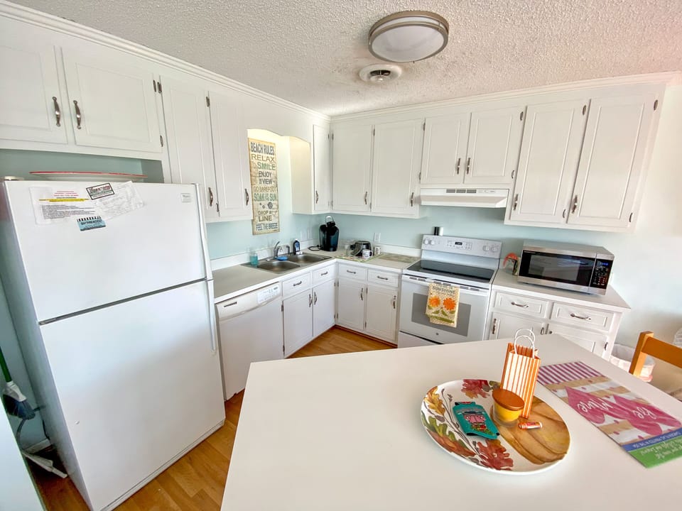 Your fully equipped kitchen awaits with bright white cabinets, modern appliances, and cheerful touches that make cooking feel like home.