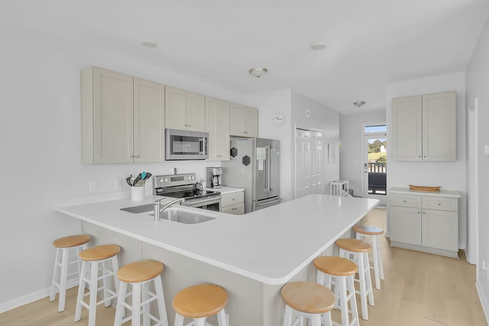 Your fully equipped kitchen features sleek white cabinets, modern appliances, and a spacious island with bar seating for memorable meal prep.