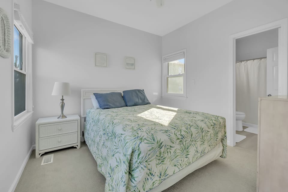 Sink into peaceful sleep in your bright bedroom, where botanical bedding and coastal whites create your perfect retreat.