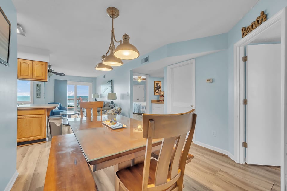 Your bright dining space features warm wood finishes and pendant lighting, with stunning ocean views through the windows.