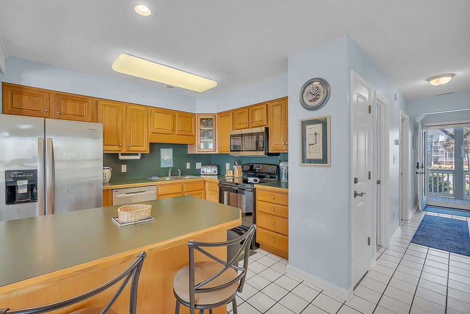Your fully equipped kitchen features warm wood cabinetry, stainless steel appliances, and a breakfast bar perfect for morning coffee.