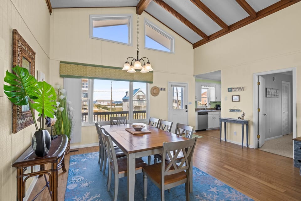 Your spacious dining room features vaulted ceilings with warm wood beams, creating an airy coastal atmosphere perfect for family meals.
