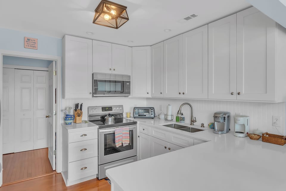 Your fully equipped kitchen features sleek white cabinets, modern appliances, and ample counter space for preparing delicious meals during your stay.