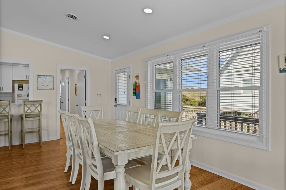 Gather around your bright dining table with coastal charm, where white furnishings and warm wood floors create the perfect space for memorable meals.