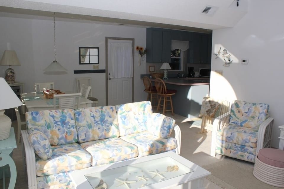 Relax in your bright, open living space with cheerful floral seating, while the fully equipped kitchen awaits your culinary adventures.