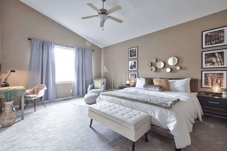 Retreat to the spacious primary suite featuring a luxurious king bed, soaring ceilings, and cozy seating area.