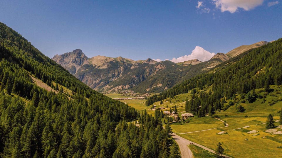 A sweeping valley of dense pine forests and open meadows nestled between the French Alps.