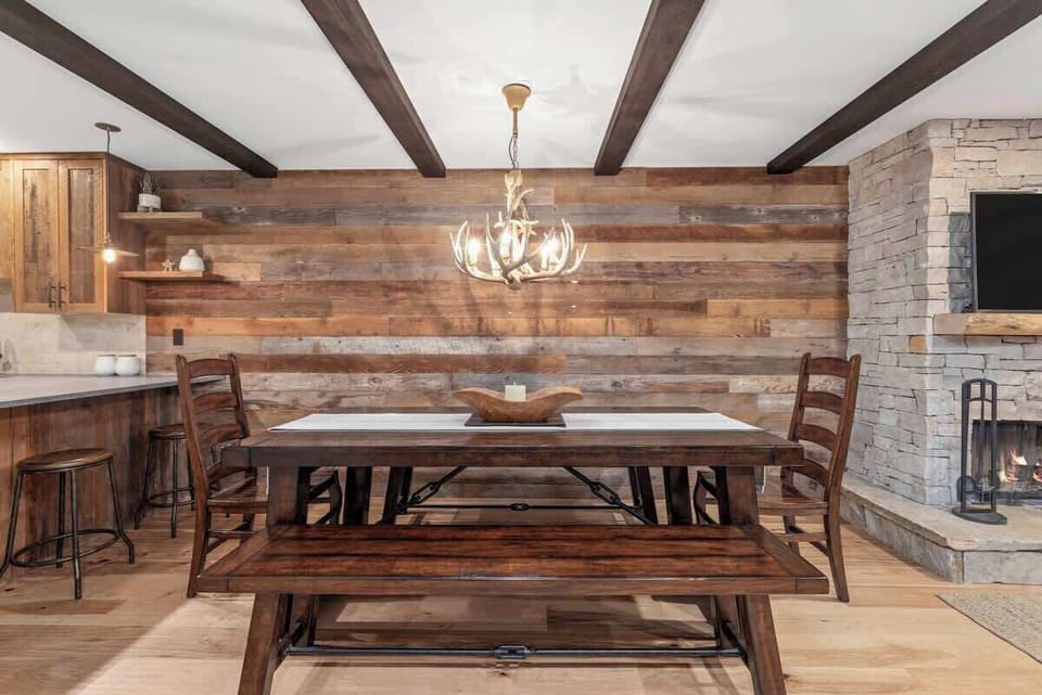 - Rustic dining area with reclaimed wood accent wall  
- Antler chandelier and timber beams create cozy warmth  
- Perfect for family dinners and après-ski gatherings  
