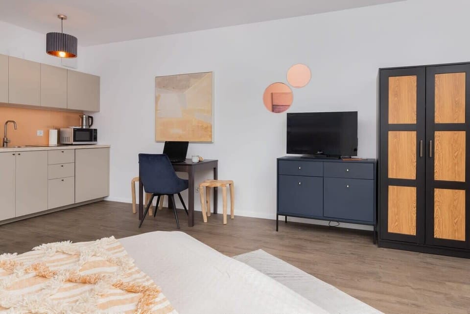 A wide shot of the living space, with a desk, TV stand, and stylish furniture pieces.






