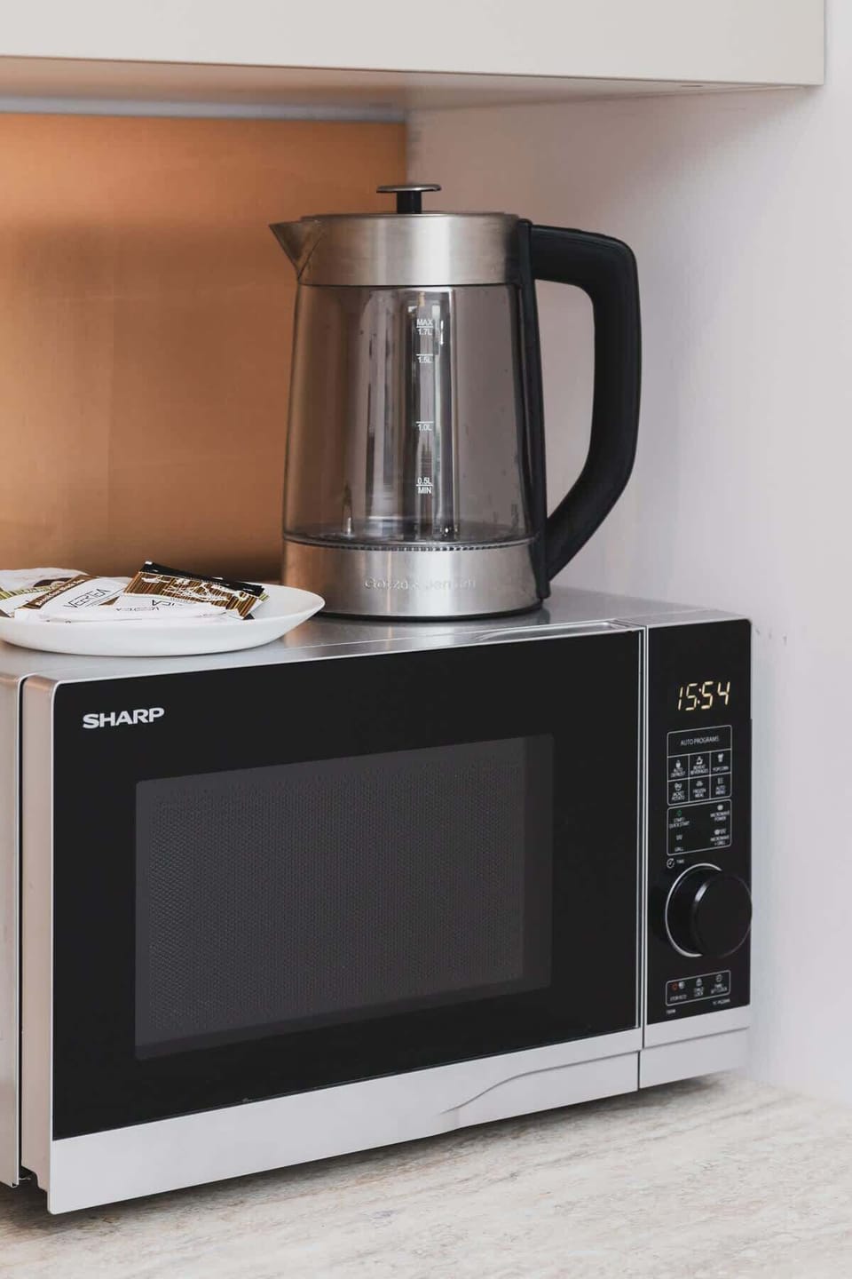 A microwave and kettle neatly placed on a wooden shelf within the kitchen.

