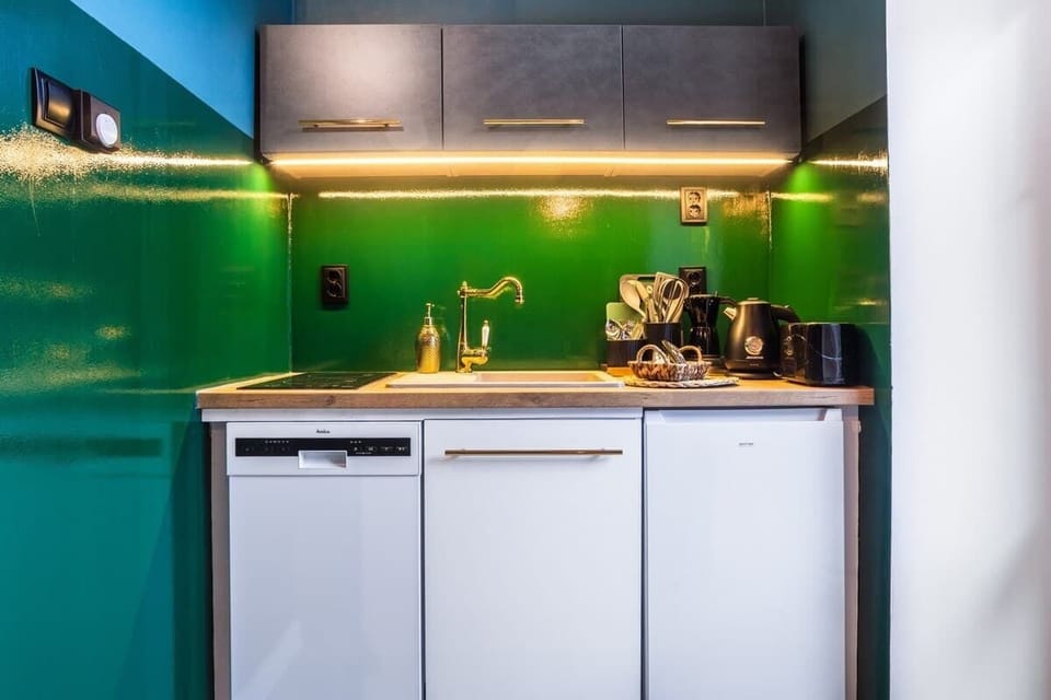 A modern kitchenette with dark cabinets, under-cabinet lighting, and gold accents.

