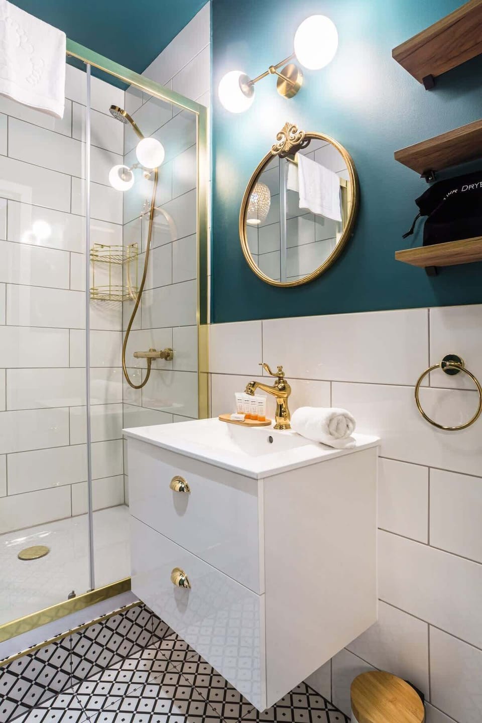 A well-lit bathroom with a modern sink, a round mirror, and gold fixtures.

