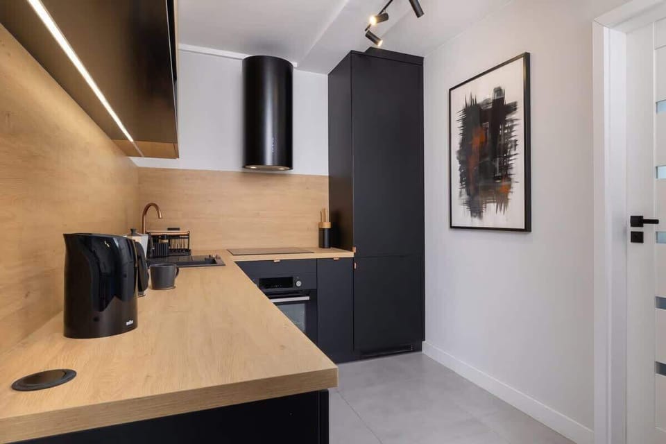 A sleek kitchen with black and wooden cabinets, modern appliances, and under-cabinet lighting.

