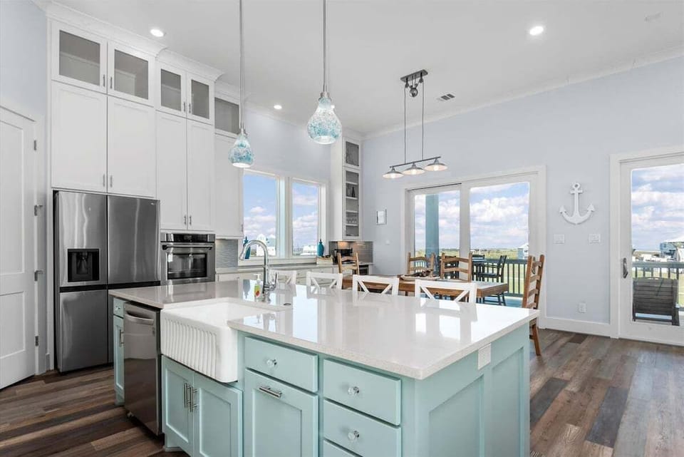 Bright chef's kitchen with oversized island, farmhouse sink, stainless appliances, and dining area with scenic outdoor views.