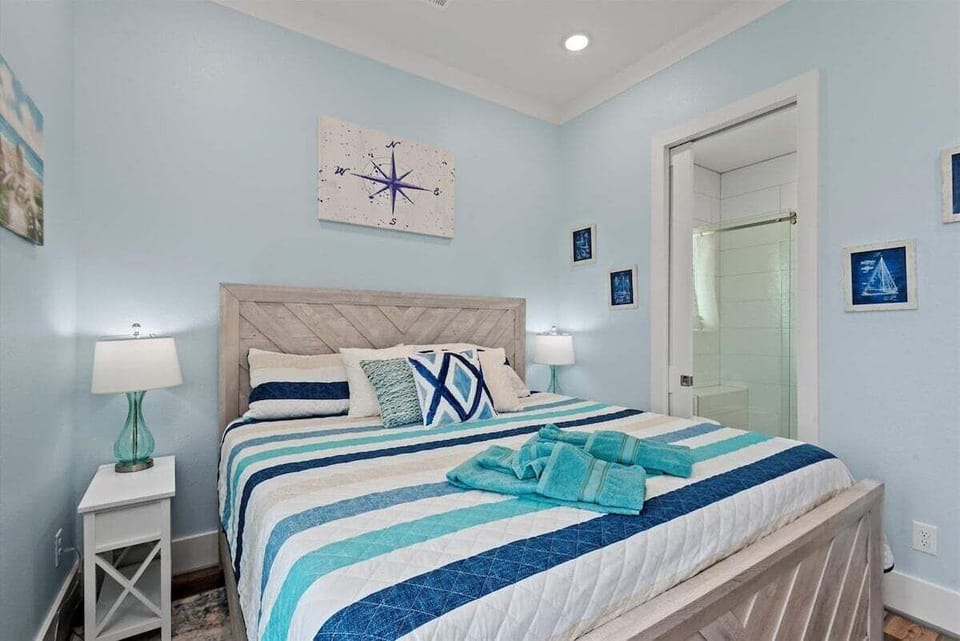 Comfortable bedroom with king bed, coastal décor, and direct access to a private ensuite bathroom.