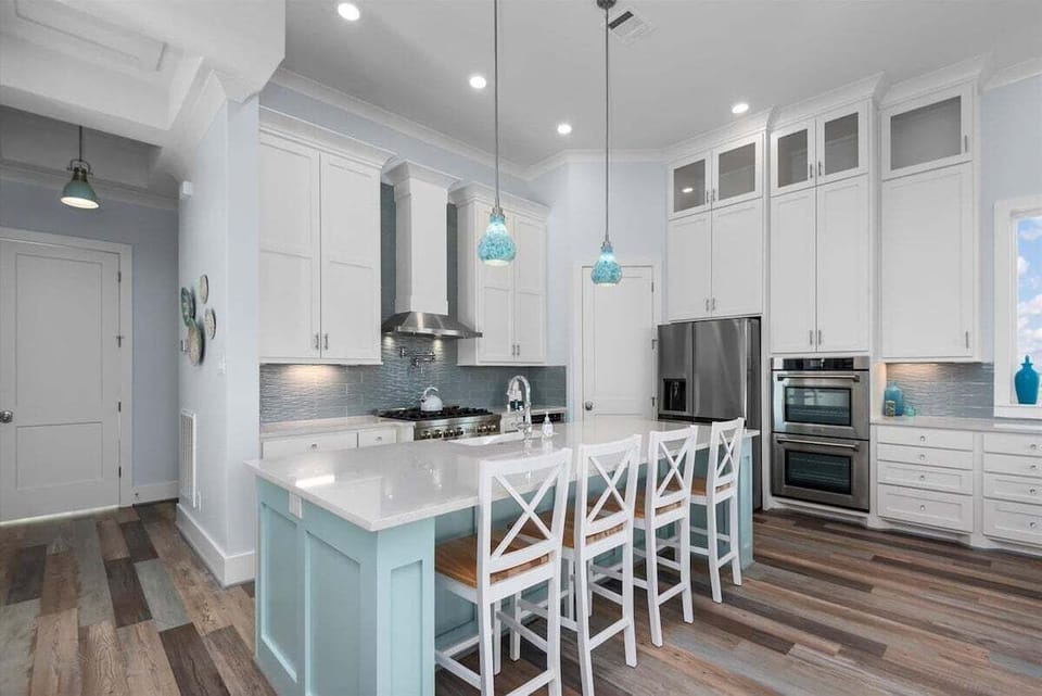 Gourmet kitchen featuring a large island, quartz countertops, stainless steel appliances, custom cabinetry, and seating for family meals.