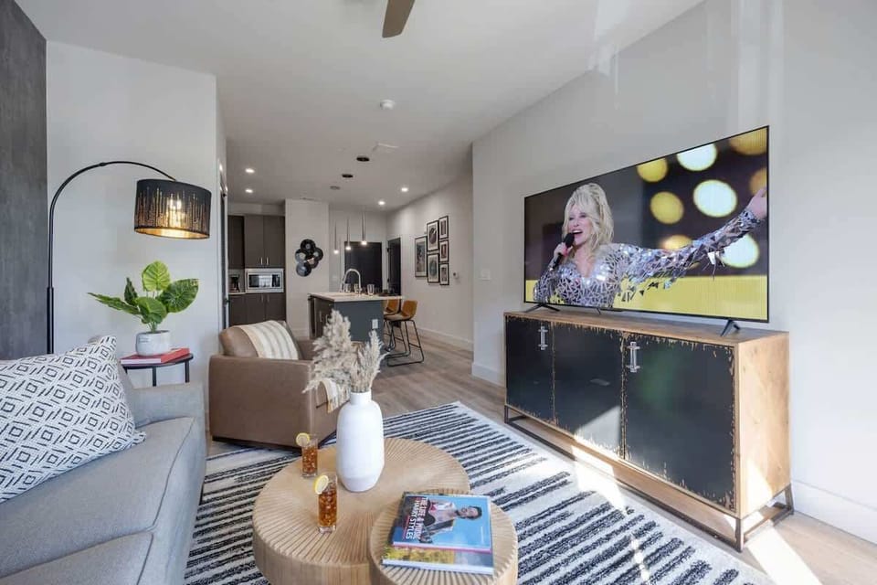 Bright open living space featuring a smart flat-screen TV, designer furnishings, and access to the patio.
