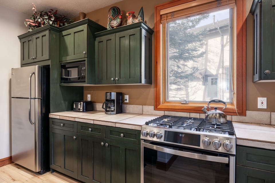 - Fully equipped kitchen with stainless steel appliances  
- Rustic green cabinets and tiled countertops for charm  
- Everything needed to cook meals and enjoy together