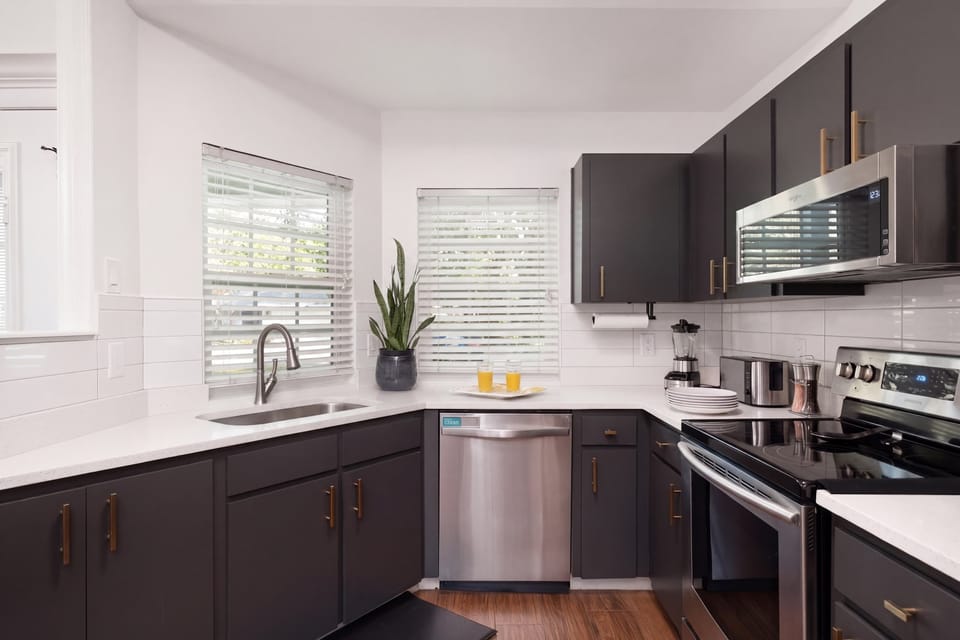 Sleek design meets daily functionality. Kitchen with a dishwasher, microwave, and full stove set against a stylish monochromatic palette—perfect for any home cook.