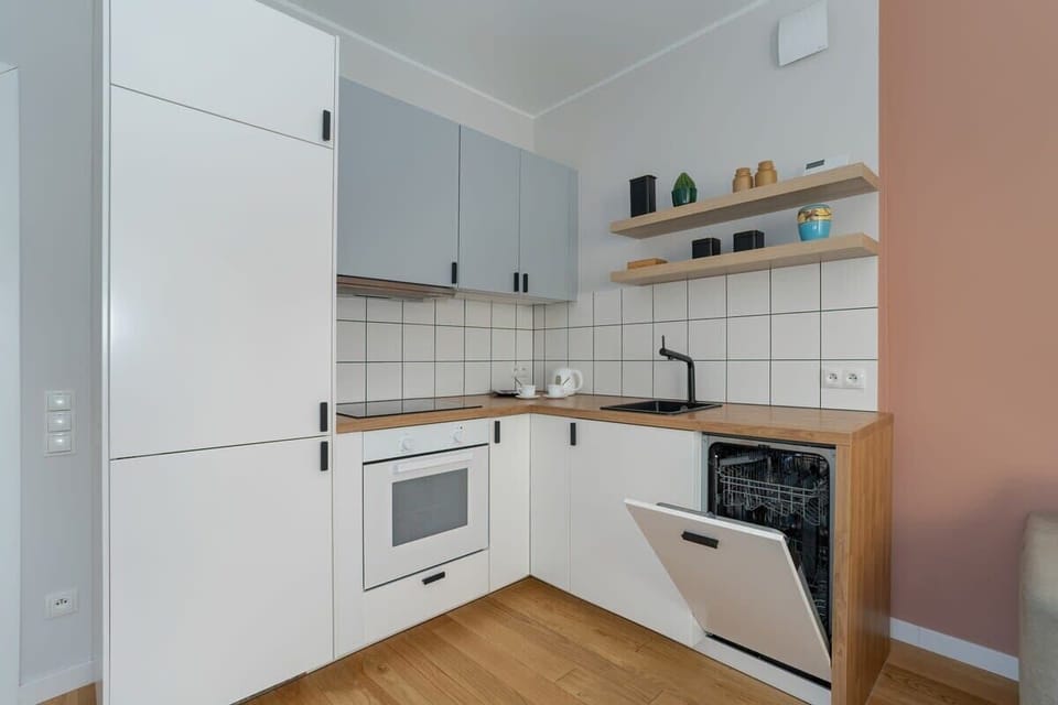 A stylish kitchen with white cabinets, wooden countertops, and tiled walls.


